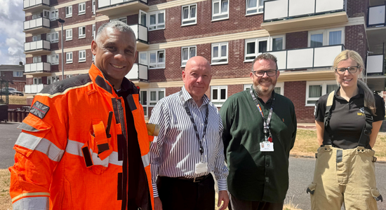 Colleagues from South Yorkshire Fire and Rescue and Berneslai Homes standing in front of a high rise flat.