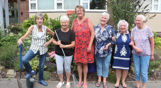 A group of tenants standing outside in front of the gardens at Pendon House.