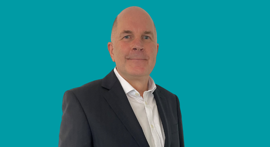 Berneslai Homes' Chair of the Board, Ken Taylor, superimposed on a light blue background.